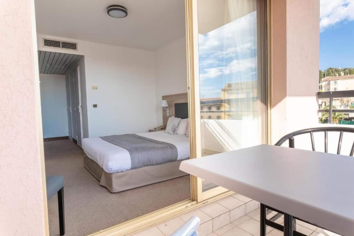 Habitación de hotel con cama, una mesa y vistas a la ciudad.