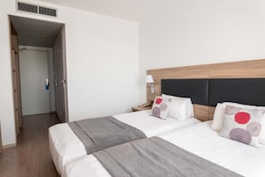 Una habitación de hotel con cama, mesitas de noche, lámpara y puerta.
