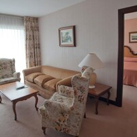 Habitación de hotel con sofá, dos sillones, una mesita de centro, lámpara y un cuadro en la pared.