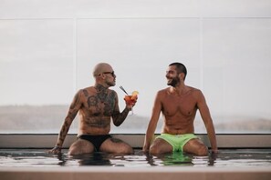 Två män i en swimmingpool med utsikt över staden.