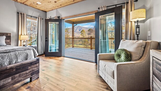 Une chambre avec un plafond en bois, un lit, un canapé et un balcon offrant une vue sur la montagne.