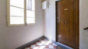 A room with a checkered floor, a wooden door, and a window with blinds.