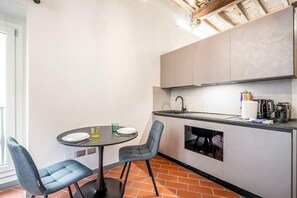A compact kitchen with a dining table and chairs, a built-in oven, and a coffee machine. - Lambertesca Mono (Florence)