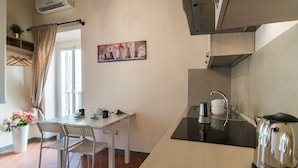 A compact kitchen with a dining table, chairs, a kettle, and a coffee maker.