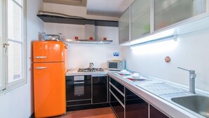 A compact kitchen with a gas stove, a microwave, and a small refrigerator. - Della Scala Modern Apartment (Florence)