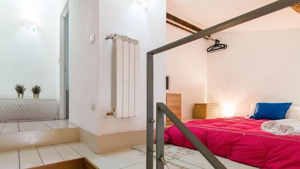 A bedroom with a bed, a wooden staircase, a radiator, and a small plant on the wall. - Della Scala Modern Apartment (Florence)