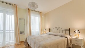 A bedroom with a bed, bedside lamps, a nightstand, and a window with curtains.