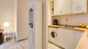 A compact kitchen with a washing machine, a coffee maker, and a sink.