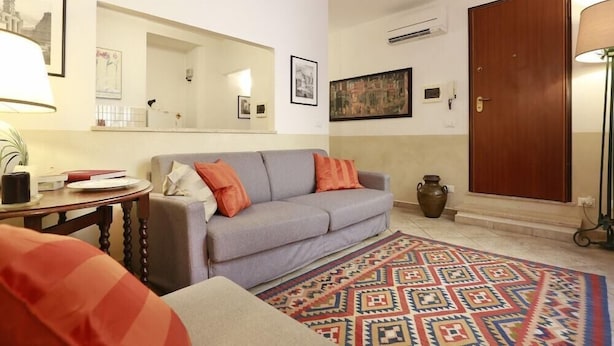 A living room with a grey sofa, a patterned rug, a wooden door, and a mirror on the wall. - Ghibellina Apartment (Florence)