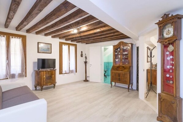 Amplia sala de estar con techo de madera, televisor, sofá y un mueble de madera grande.