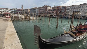 A gondola docked at a canal in Venice, surrounded by historic buildings and wooden poles. - Residenza Valier (Venice)