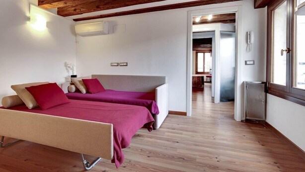 A modern bedroom with two beds, wooden flooring, and a rustic ceiling. - Residenza Valier (Venice)
