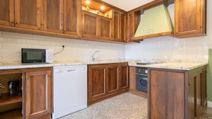 Una cocina con armarios de madera, un microondas, un lavavajillas y un lavabo.