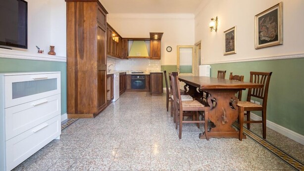 Una cocina con armarios de madera, encimera de granito y comedor con mesa y sillas de madera.