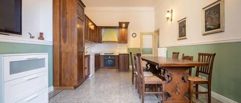 A kitchen with wooden cabinets, a granite countertop, and a dining area with a wooden table and chairs.