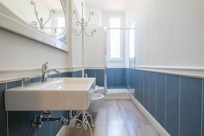 A bathroom with a white sink, a mirror, and a glass shower enclosure. - Santa Maria Novella 4 Bedrooms (Florence)