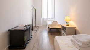 Una habitación pequeña y limpia con cama, mesita de noche, lámpara y un escritorio con silla.
