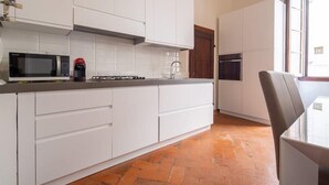 A modern kitchen with white cabinets, a microwave, a coffee machine, and a stove. - Lian Home in Florence (Florence)