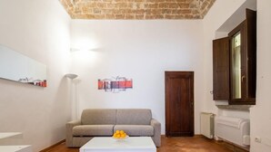 A living room with a sofa, a coffee table with fruit, a lamp, and a door. - Lian Home in Florence (Florence)