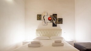 A hotel room with a large bed, a white headboard, and a wall-mounted artwork. - Lian Home in Florence (Florence)