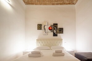 A hotel room with a large bed, a white headboard, and a wall-mounted artwork. - Lian Home in Florence (Florence)