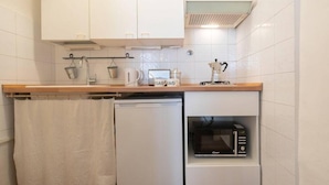 A compact kitchen with white cabinets, a microwave, and a coffee maker.