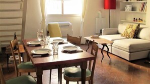 A dining area with a wooden table set for four, a sofa, and a red floor lamp.