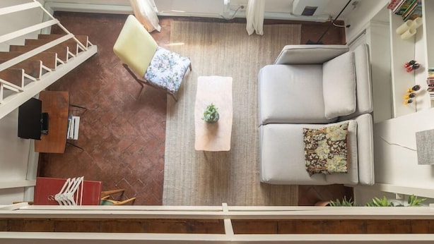 A spacious living area with a sofa, a coffee table, and a chair. A staircase is visible in the background.