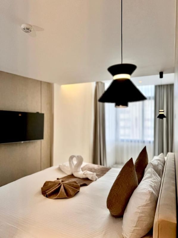 A modern hotel room with a bed, pillows, a flat-screen TV, and a ceiling light fixture. - Merryland Hotel Amman (Amman)