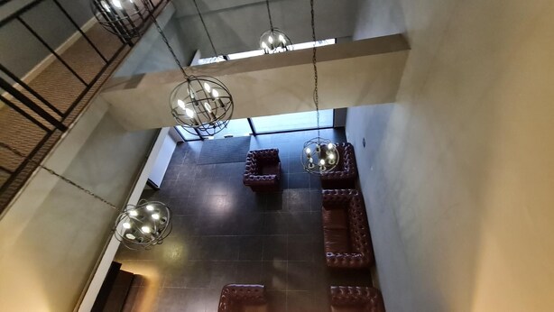 A high-ceilinged interior with exposed beams, a dark tiled floor, and a central seating area with a cushioned bench. - Geo Boutique Hotel - Seri Kembangan (Seri Kembangan)