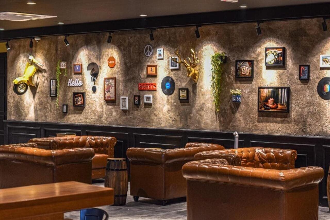 A bar area with leather sofas and a wall decorated with framed pictures and a yellow scooter.