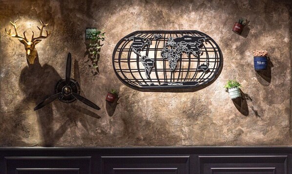 Un mur orné d’une carte du monde décorative, un ventilateur fixé au mur et plusieurs plantes en pot.