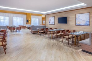 A modern hotel dining area with multiple tables and chairs, a sofa, and artwork on the walls. - Residence Inn Dammam by Marriott (Dammam)