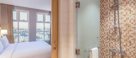 A hotel room with a bed, a shower, and a city view.