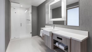 A modern bathroom with a glass shower enclosure, a large mirror, and a vanity with a sink and towel rack. - Springhill Suites by Marriott Auburn (Auburn)