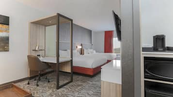 A hotel room with a bed, a desk, a chair, a TV, and a coffee machine.