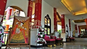 Un interior tradicional con columnas rojas, un mural y un soporte escalonado con flores.