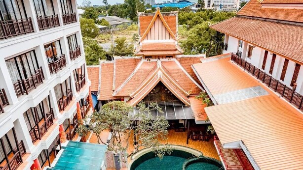 Un hotel con piscina central, varios balcones y arquitectura tradicional.