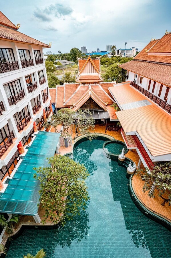 Ein Hotel mit zentralem Schwimmbad, mehreren Balkonen und traditioneller Architektur.