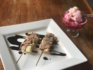 Ein Dessertteller mit in Schokolade getauchten Bananen am Spieß und einer Schüssel Eis.