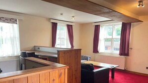 A room with a wooden partition, a dining table, a sofa, and a window with curtains. - The Knighton Hotel by Payman Club (Knighton)