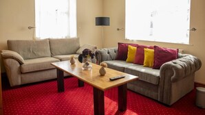 A living room with two sofas, a wooden coffee table, and a floor lamp. - The Knighton Hotel by Payman Club (Knighton)