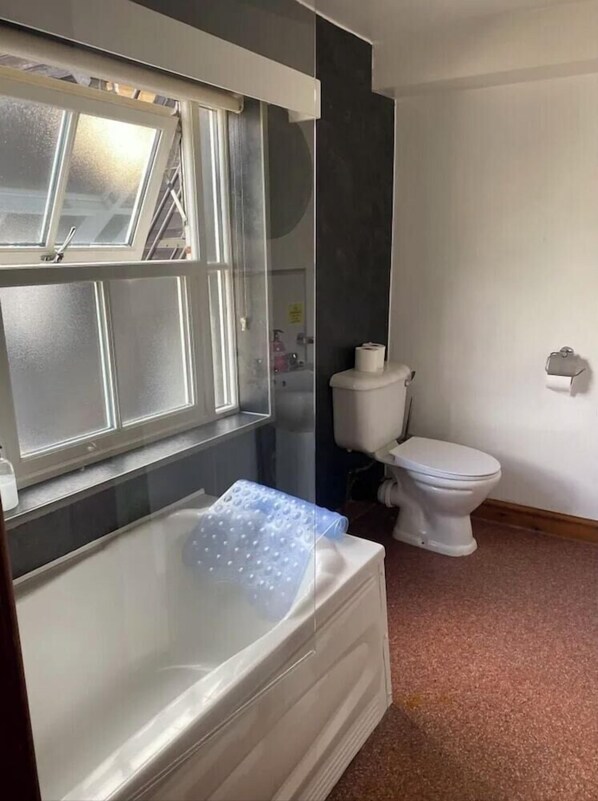 A bathroom with a bathtub, toilet, and a window. - The Knighton Hotel by Payman Club (Knighton)
