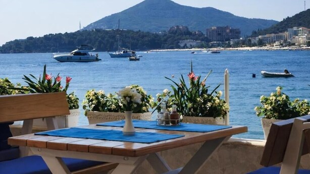An outdoor seating area with a view of the sea, boats, and a mountain. - Hotel Ponta Nova (Bečići)