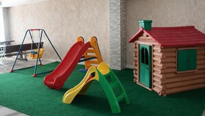 A children's play area with a slide, swing set, and a log cabin playhouse. - Hotel Ponta Nova (Bečići)