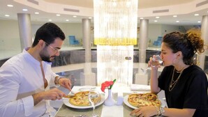 A dining area with a chandelier, a table with plates of food, and a vase with a flower.