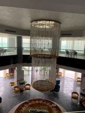 Un hall d’entrée spacieux, agrémenté d’une colonne décorative centrale, de plusieurs espaces de détente et de grandes fenêtres offrant une vue dégagée.