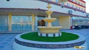 A hotel with a central fountain, outdoor seating, and a tiled patio area.