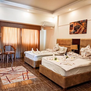 Une chambre d’hôtel avec deux lits, une chaise, un tableau et un appareil de climatisation.