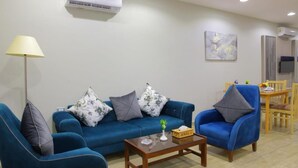 A living room with a blue sofa set, a wooden coffee table, and a lamp.